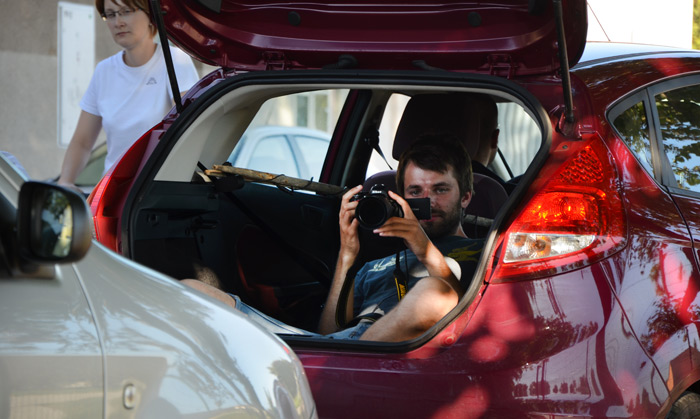 Kameraman ležel v otevřeném kufru auta, snímaje vozy jedoucí za ním